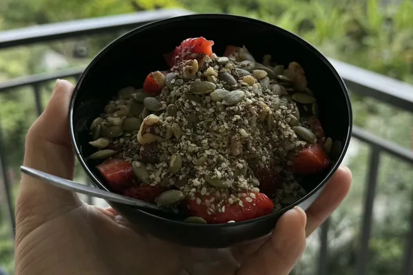 A hand holding a serving of the seed and nut mix